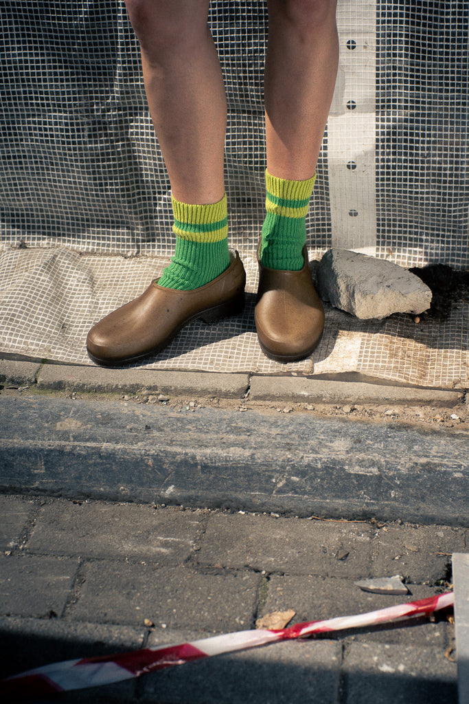 Person wearing green socks with yellow stripes made of wool and cashmere 