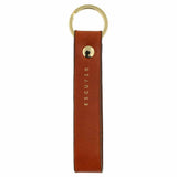 Escuyer cognac leather keychain — Italian vegetable tanned leather tab with gold metal ring and gold Escuyer logo