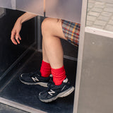 Person wearing red socks and black sneakers stepping out of a door.