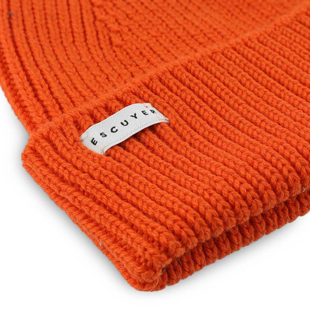 Side view of bold orange ribbed merino wool beanie with folded cuff