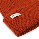 Side view of orange ribbed merino wool beanie with folded cuff